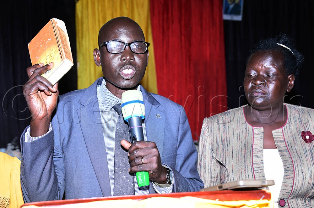 Isaac Okello Omiat taking oath as his wife looks on. (Credit: Godfrey Ojore)