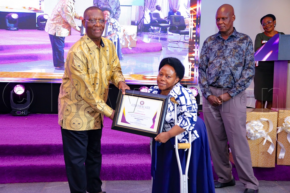 Pius Bigirimana, the judiciary PS, handing over a certificate of recognition to a retiring judiciary support staffer at the Supreme Court conference hall on Tuesday, December 16, 2025. (Photo by Farooq Kasule)