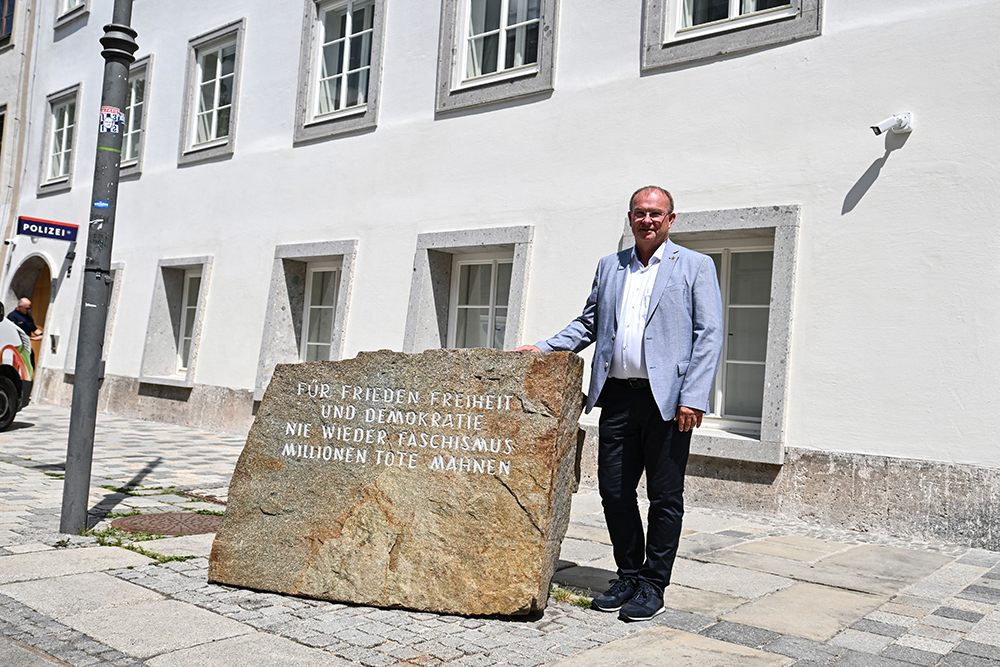 Braunau&rsquo;s mayor Johannes Waidbacher poses on July 16, 2026 next to a commemoration stone with the inscription "For peace in freedom and democracy. 