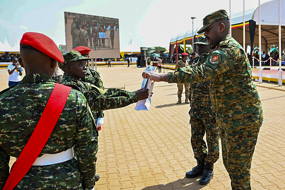 Chief of Defence Forces (CDF) Gen Muhoozi Kainerugaba presents the Order of the Commander in Chief award to the best overall student recruit, Amanya Sarah, during the passout at Kaweweta on Thursday. (PPU Photo)
