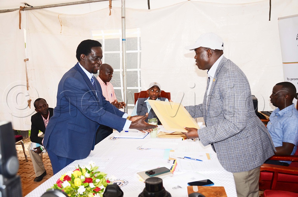 Tobias Lugolobi who picked nomination forms from Samuel Kiyingyi the principal electoral commission officer (right) at EC headquarters in Kampala. (Photo by Isaac Nuwagaba)