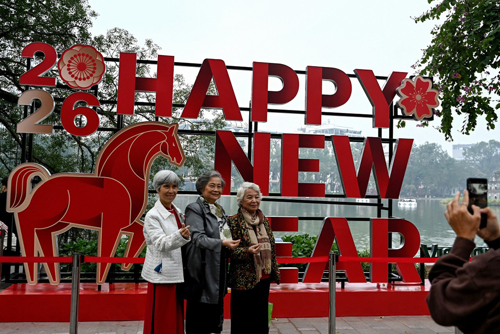 Women pose for photos by Hoan Kiem Lake next to a New Year installation in Hanoi on December 31, 2025. (AFP)