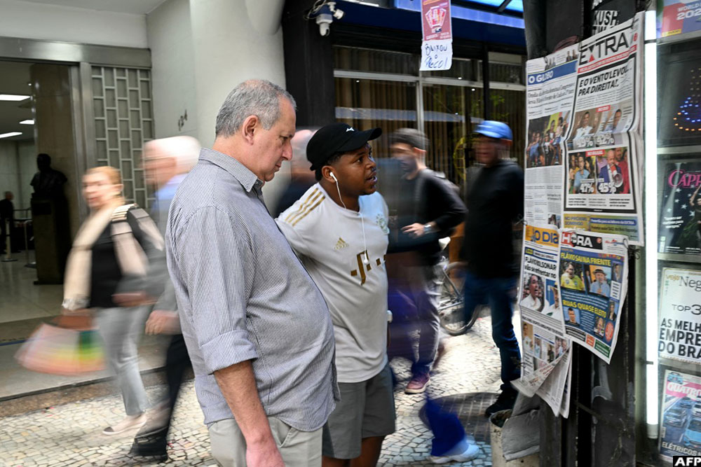 Men look at newspapers displaying coverage of Brazil's presidential election results at a newsstand in Rio de Janeiro, Brazil, on October 5, 2026. (AFP)