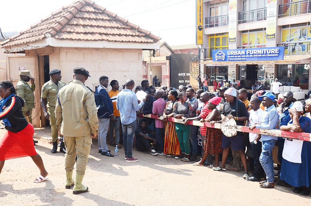 Voters at Pepsi Cola Village Industrial Area First Street listening to their names as they were read before voting on Tuesday, July 28 2026. (Photo by Isaac Nuwagaba)