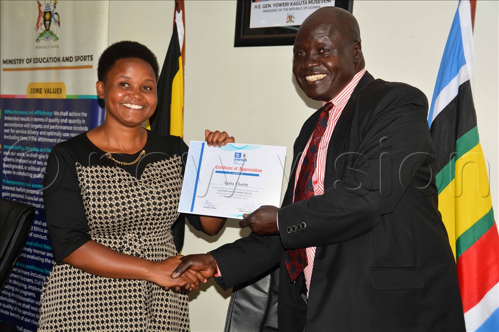 The Deputy secretary general UNESCO Uganda Dr. Dominic Mundrugo Ogo-Lali ( right) handsover a certificate to the outgoing UNATCOM youth committee chairperson Charity Agaba during the new leadership handover ceremony in Kampala. 