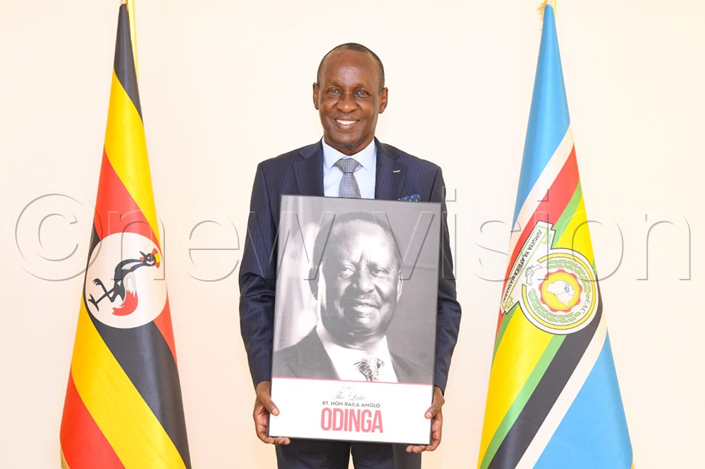 The National Chairman of the Pan-African Movement Uganda Chapter, Capt. Mike Mukula, posing for a photo with the portrait of the late Raila Odinga. (Credit: Richard Sanya) 