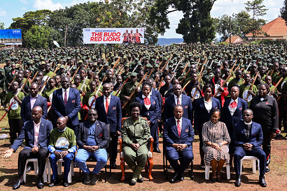 Commissioner Patriotism Helen Seku (C), the Headteacher and staff of Kings College Buddo pose for a photo with over 2500 patriotism students during their passout at Buddo on Saturday. (PPU Photo)