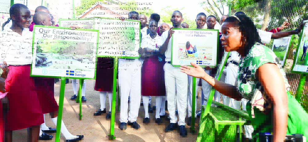 Akol (right) addressing students during the cementing of signposts at Kololo SSS yesterday
