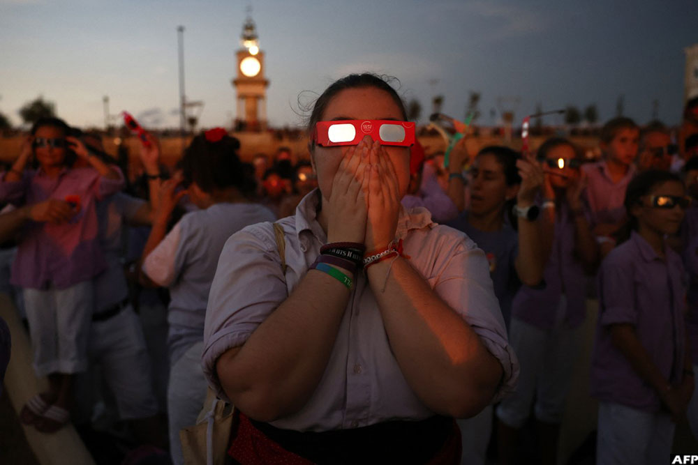 People react as they observe the total solar eclipse from the sea port of Tarragona, northeastern Spain, on August 12, 2026