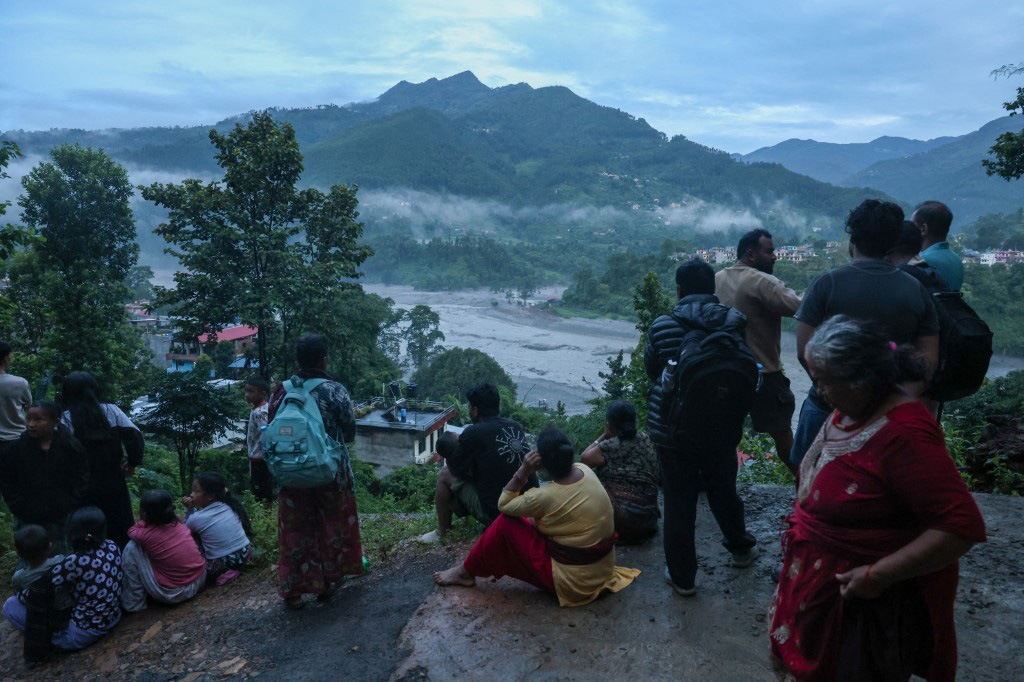 Residents living along the Trishuli River take shelter at higher ground after fleeing their homes early in the morning, as authorities issue a new flash flood warning, in Bidir, Nuwakot, Nepal, on August 30, 2026. (Photo by Daniel Ceng / Anadolu via AFP)