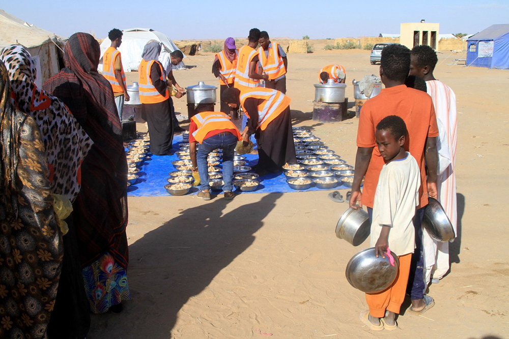 Sudanese who fled El-Fasher queue to receive free meals at the Al-Afad camp for displaced people in the town of Al-Dabba, northern Sudan, on November 20, 2025. (Photo by Ebrahim HAMID / AFP)