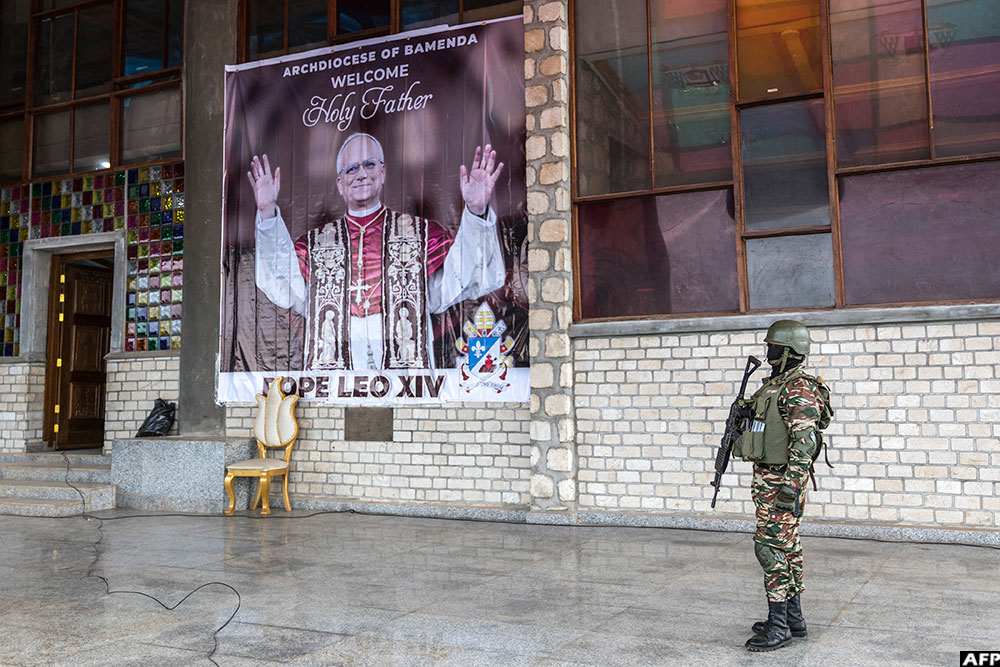 A Cameroonian solider stands guard next to a poster welcoming Pope Leo XIV ahead of his visit as local and Vatican authorities visit Saint Joseph Metropolitan Cathedral in Bamenda, on April 12, 2026