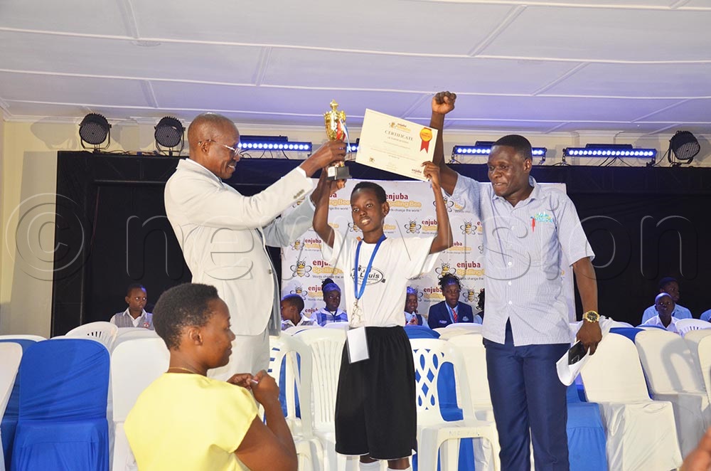 Dr. Charles Kanyesigye, the guest speaker at the Wakiso ejuba spelling bees handing over the trophy to Jonathan Kato of St Louis Pre Primary School after winning the junior category. (Credit: Isaac Nuwagaba)