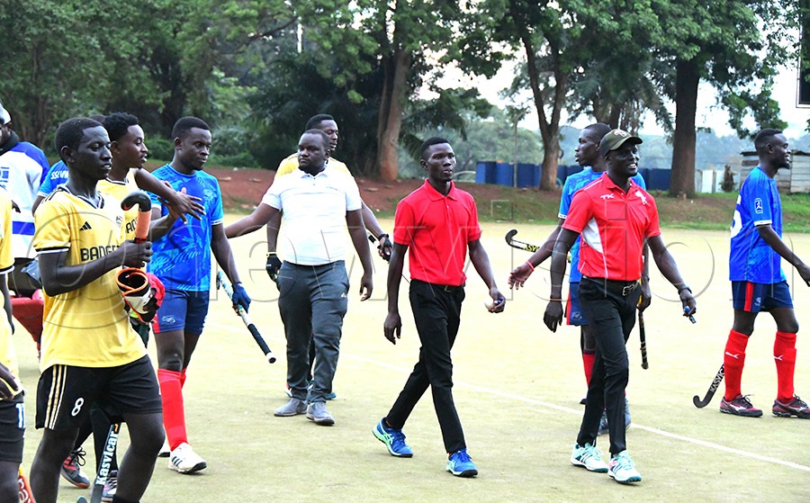 Match umpires Innocent Ascar (top) and Ronald Oketayot leave the pitch while Stallions Hockey Club coach Marktum Muziransa gathers his players after the match on April 20, 2026, at Lugogo. Photo by Silvano Kibuuka