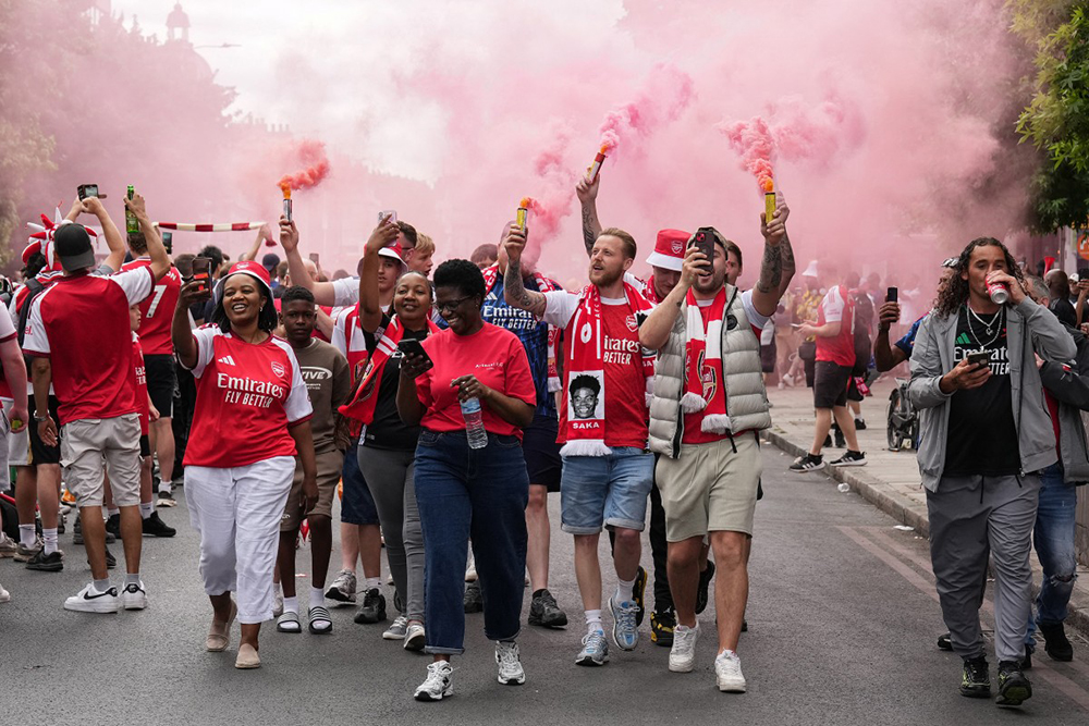 Arsenal supporters light flares as they wait for the start of the parade along the route to celebrate Arsenal's men team's Premier League title during celebrations outside the Emirates Stadium in London on May 31, 2026. It is the first Premier League title for the North London team since the 2003-04 season. 