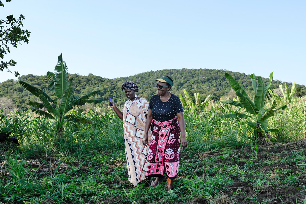 Domitila Mueni (L), 54, serving as a Treasurer of a local Community Forest Association (CFA) visits with one of her  neighbours, Eunice Mwoki (R), 56, at her farm, juxtaposed against the Mrima Hill Forest in Lunga-Lunga, Kwale county on September 26, 2025. (Photo by Tony KARUMBA / AFP)