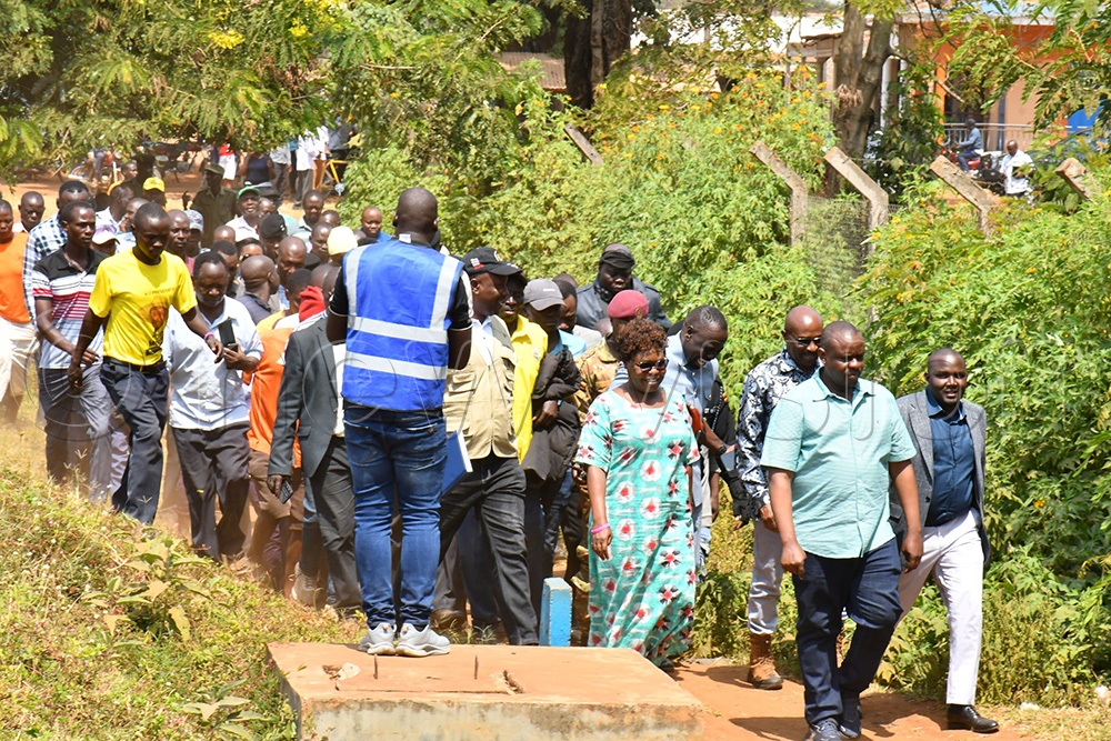 The Minister of Local Government, Balaam Barugahara (in front), with Bulambuli district leaders walking towards Muyembe Health Centre IV to inspect the sh73m toilet built without a pithole. (Photo by Donald Kiirya)