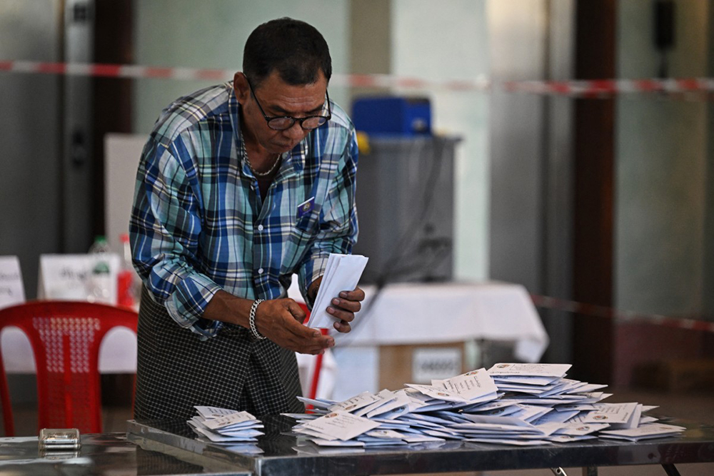 A member of Myanmar’s Union Election commission (UEC) prepares to count ballots after the closing of polls at a polling station in the first phase of Myanmar’s general election in Yangon on December 28, 2025. (Photo by Lillian SUWANRUMPHA / AFP)