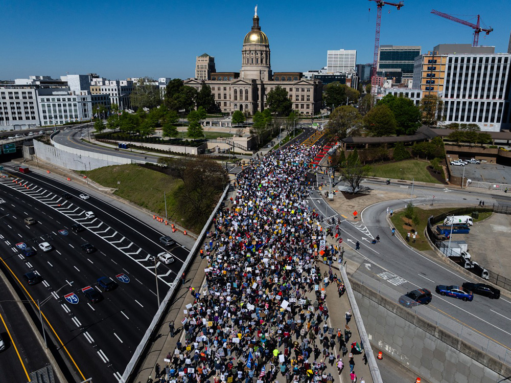 An aerial view shows people marching near the Georgia state Capitol building during the "No Kings" national day of protest in Atlanta, Georgia, on March 28, 2026. (Photo by Elijah Nouvelage / AFP)