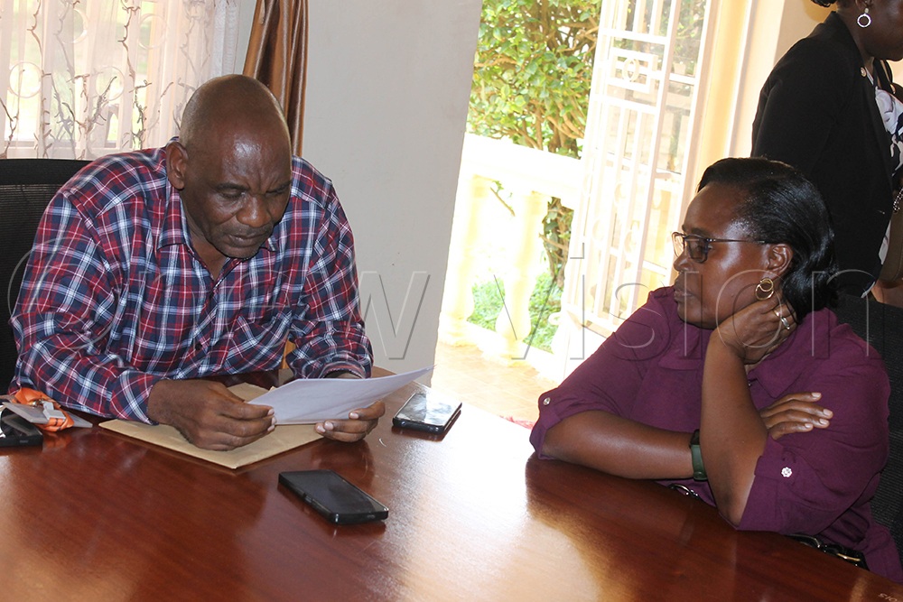 James Magezi (left), an officer from the Inspectorate of Government (IGG), reads a statement to suspect Peace Kebirungi, a former office typist at Ntare School, shortly before her arrest at the IGG’s Mbarara Regional Office on Wednesday. (Photo by Abdulkarim Ssengendo)