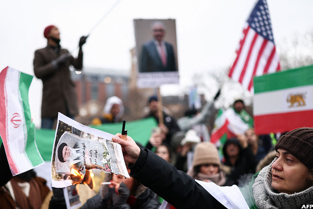 A woman burns a photo of Iranian Supreme Leader, Ali Khamenei, as people sing and shout during a rally in support of the Iranian people in New York, on January 18, 2026