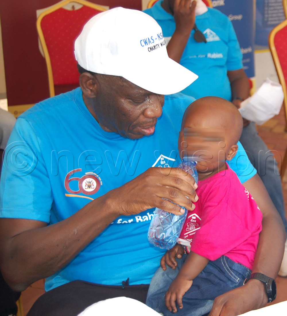 Bank of Uganda Governor Dr. Michael Atingi-Ego giving water to a baby during the function. (Photo by Mathias Mazinga)