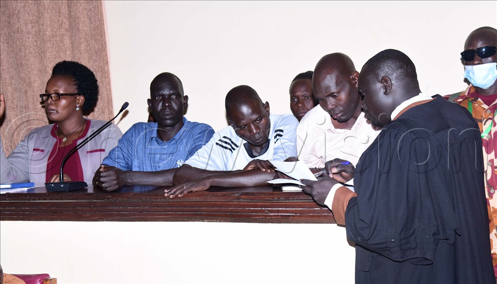 Lawyer Francis Ajum assigned by the state to represent the accused, consulting with Obotol during court proceedings. 