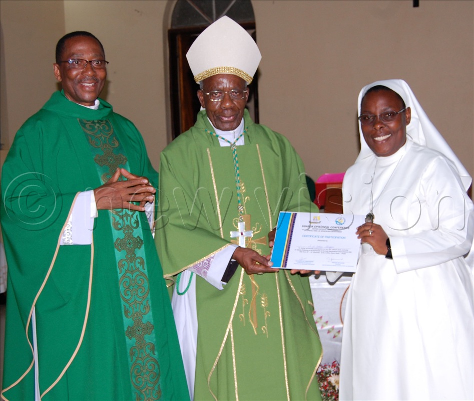 Archbishop Augustine Kasujja (centre) hands over a certificate of attendance to Rev. Sr. Mary Justine Naluggya (right) as Fr Fred Tusingire (left) looks on.
