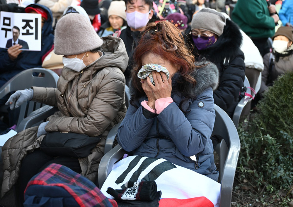 Supporters of South Korea's impeached former president Yoon Suk Yeol react as they watch a live stream of Yoon's trial on his insurrection charges near the Seoul Central District Court in Seoul on February 19, 2026. (AFP)
