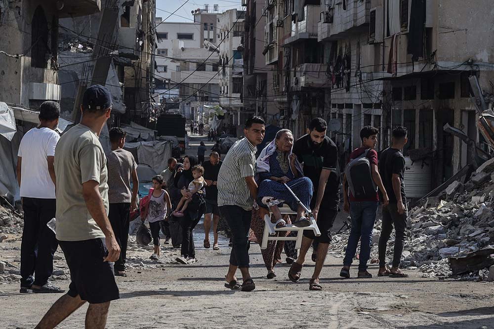 People are seen amid debris as some carry an elderly woman after Israel targeted the area near Abbas Junction in western Gaza City, Gaza on August 08, 2025. (Credit: AFP)
