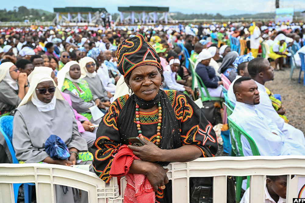 A woman poses for a photograph as Pope Leo XIV leads the Holy Mass at Bamenda Airport in Bamenda