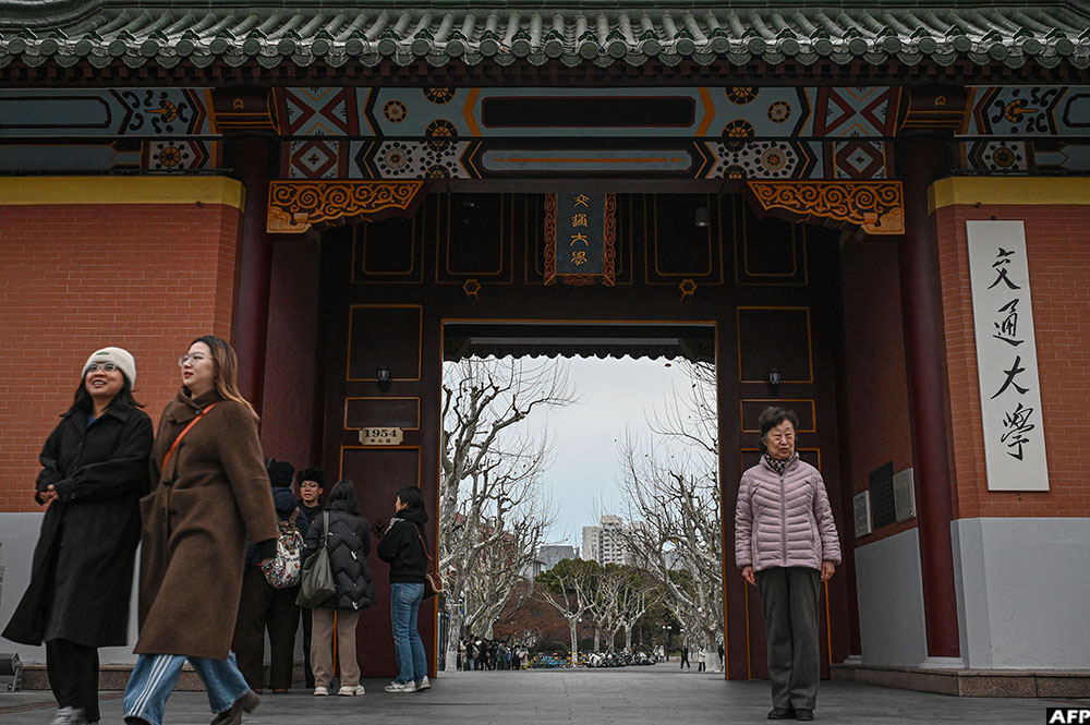 An elderly woman (R) poses for a photo at an entrance of the Shanghai Jiao Tong University in Shanghai