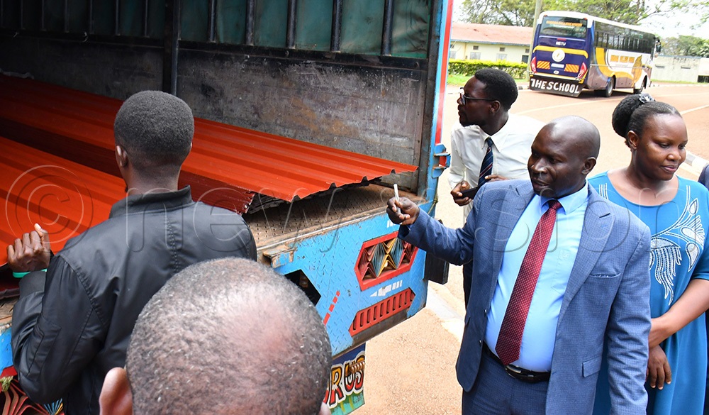  Busoga College Mwiri's headmaster Peter Sibukule (2nd right) gazing at the iron sheets that were donated by ENABEL at the school to replace asbestos, on November 6th. Looking on right is the deputy headteacher of the school Rev. Xavier Tino. (Photo by Donald Kiirya)