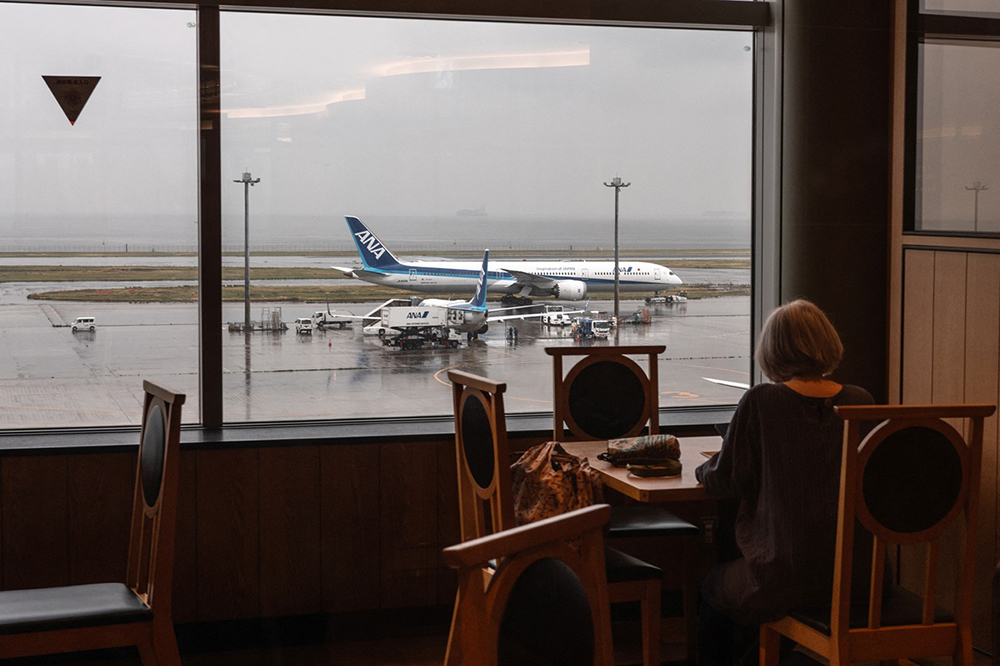 An All Nippon Airways (ANA) Boeing 787-10 passenger aircraft is seen past the window of a restaurant at Tokyo's Haneda Airport on April 23, 2026. (AFP)