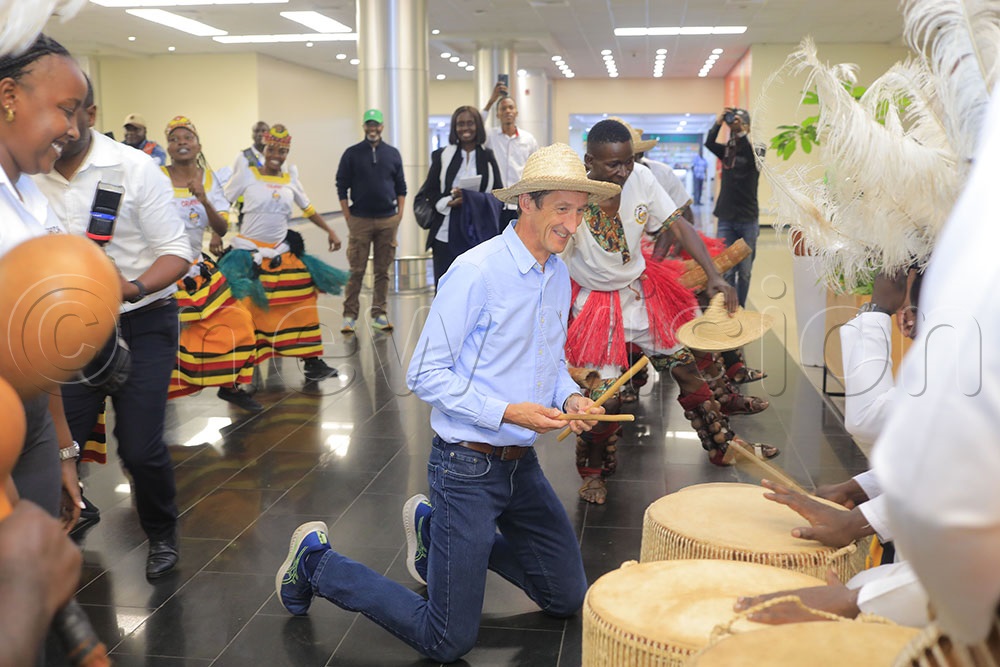 Rob Walker trying out the drums at the UTB stall as he was being welcomed by Crane permormers troupe upon his arrival at Entebbe airport on Friday night. (Credit: Julius Luwemba)