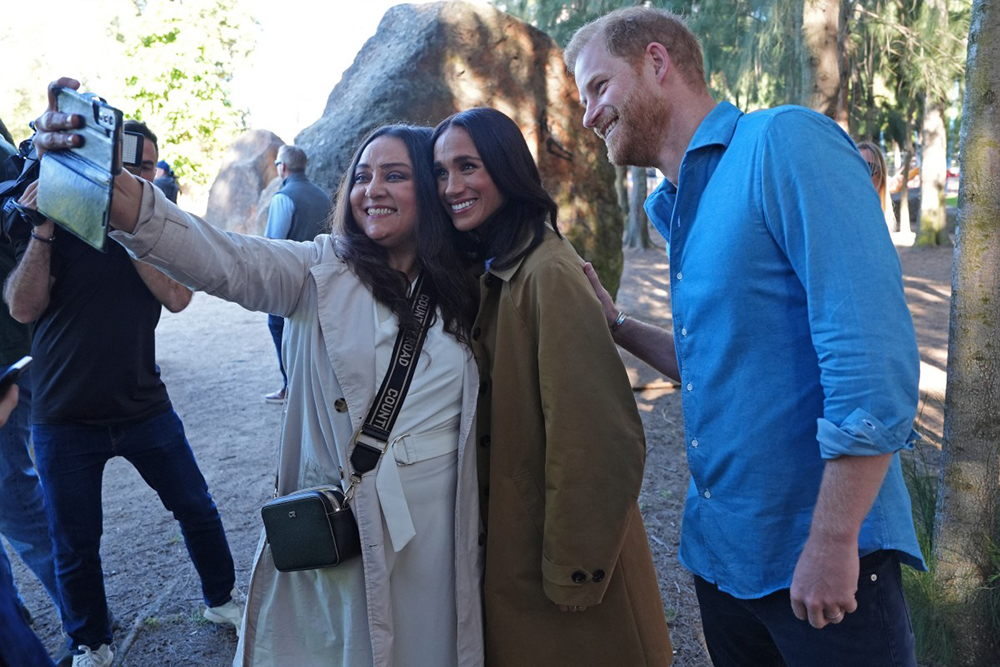 Britain's Prince Harry (R), Duke of Sussex, and his wife Meghan (C), the Duchess of Sussex, pose for a photo as they take part in the Scar Tree Walk in Melbourne on April 16, 2026. 