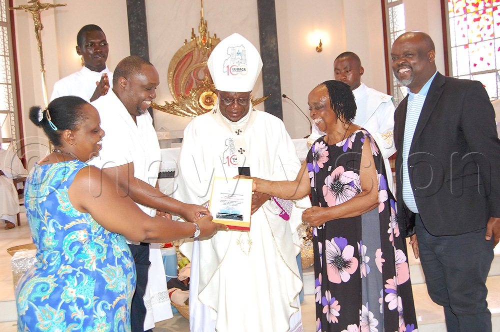 Family members receiving an accolade from Archbishop Paul Ssemogerere. (Photo by Mathias Mazinga)
