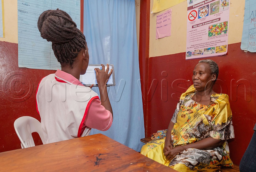 The in-charge of Naminage Health Center II Winfred Mukodha attends to a patient using the electronic management records system. (Credit: Agnes Kyotalengerire)