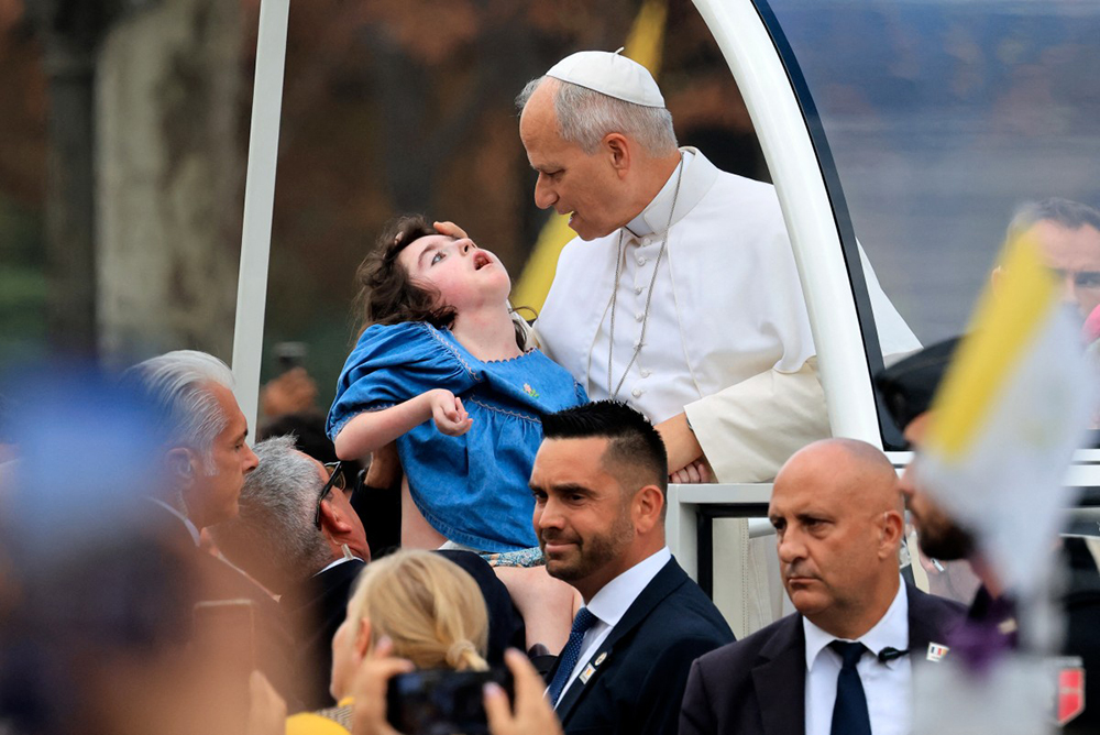 Pope Leo XIV blesses a child as he rides down the Champs-Elysees Avenue in the Papamobile (popemobile) on his way to the Place de la Concorde, central Paris, on September 26, 2026, to celebrate a solemn outdoor mass, on the second day of his visit to France. (AFP)