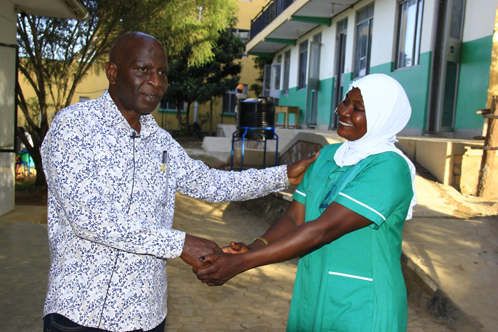 Birungi with the school&rsquo;s director, Benon Mugume handshaking.