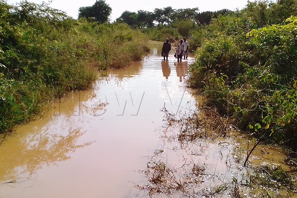 Residents walk through their flooded feeder road.