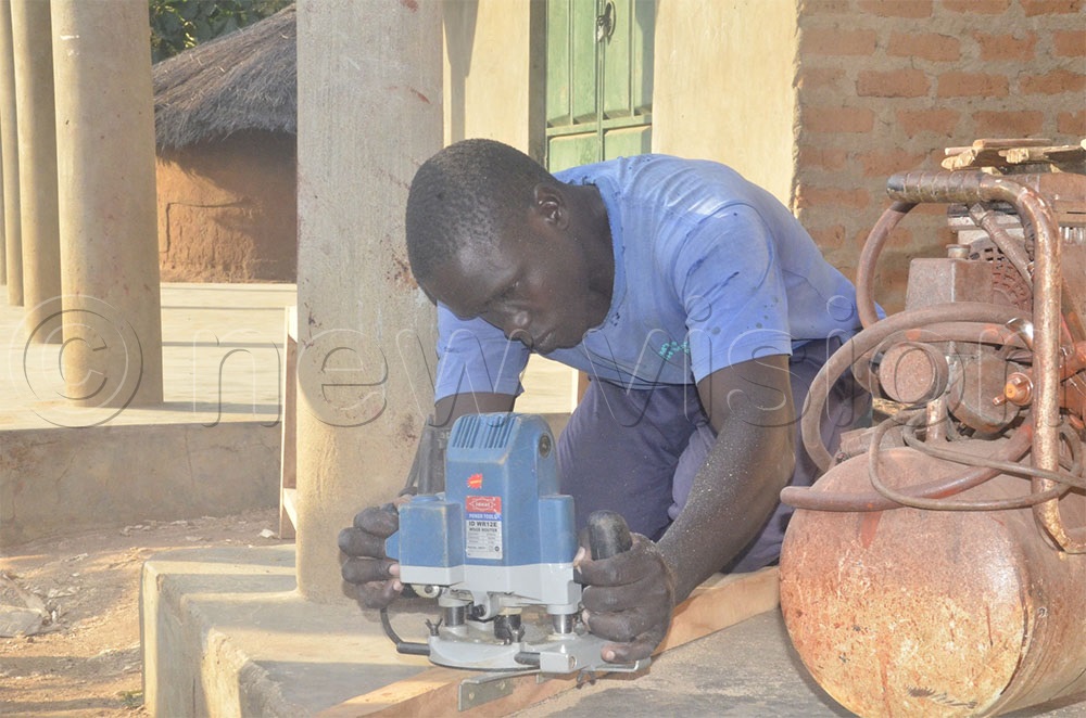 Matthew Ariko, a carpenter working in Magoro with an electric-powered timber moulding machine, shared that the income from his workshop has allowed him to support his young family, describing the development as a milestone in his life. (Credit: John Masaba)
