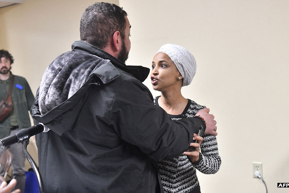 US Representative Ilhan Omar (R) reacts after being sprayed with an unknown substance by a man as she hosted a town hall in Minneapolis