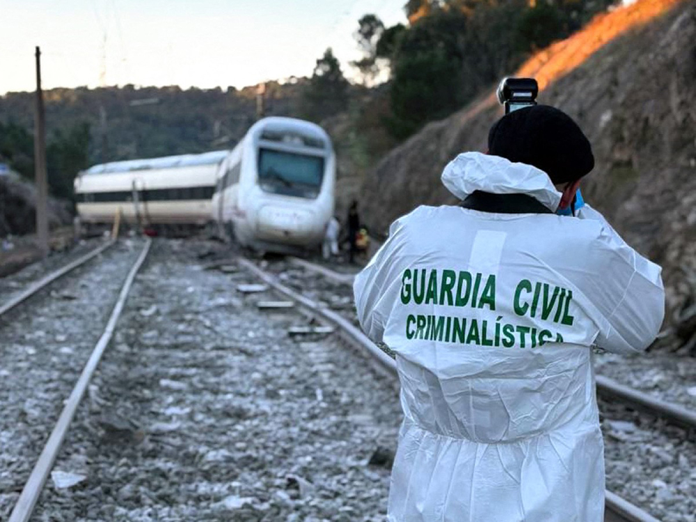 In this handout photo taken and released on January 19, 2026 by the Spain's Guardia Civil investigates at the site where a high-speed Iryo train derailed and was hit by another train as rescue efforts continue in Adamuz, southern Spain, on January 19, 2026. 