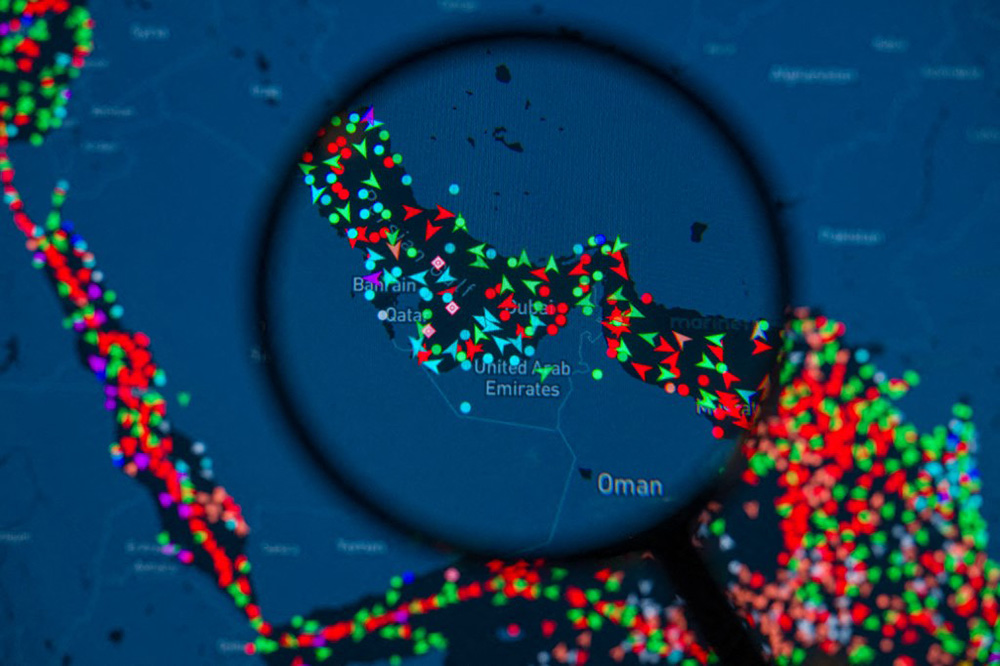 A MarineTraffic map showing ship movements in the Strait of Hormuz is pictured through a magnifying glass in this photo illustration, as commercial vessel traffic through the key oil shipping lane drops sharply amid the escalating conflict involving Iran. (Photo by Jonathan Raa / NurPhoto via AFP)