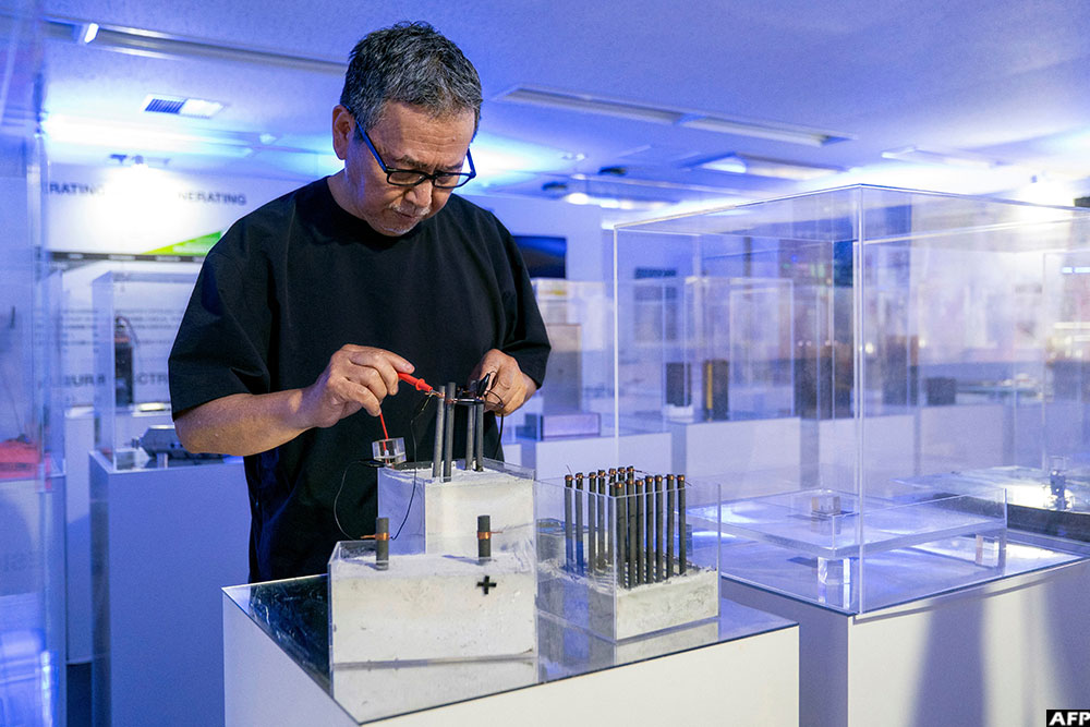 Japanese product designer and engineer Satoshi Nakagawa conducting an experiment to harvest electricity from a block of concrete at his laboratory in Tokyo.