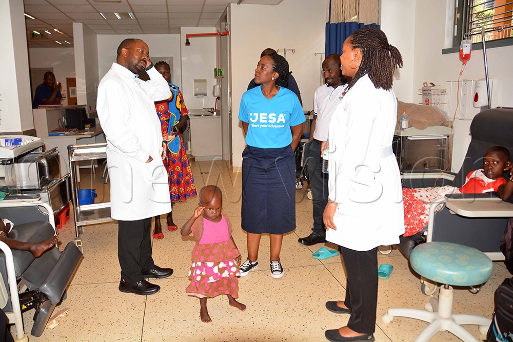 The lab director and head of research and training at Uganda Cancer Institute, Nixon Niyonzima (left) briefing an official from JESA  Farm Dairy Barbara Kizza (centre) during the tour at the children's cancer ward after donating nutrition items. (Photo by Francis Emorut)