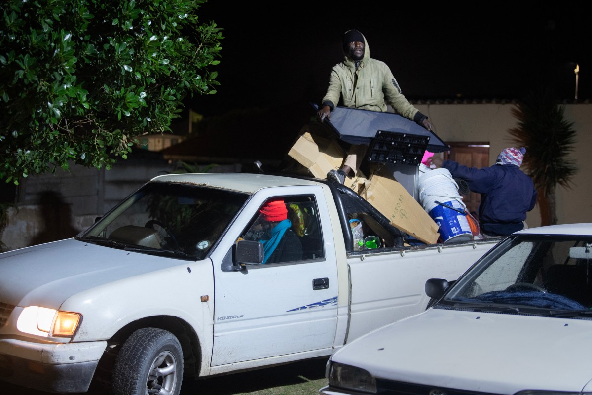 Immigrants arrive with their belongings at a community hall to take refuge in Gansbaai, about 140km from Cape Town, on June 2, 2026, after they were threatened in the communities in which they live. (Credit: AFP)