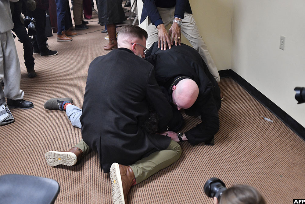 The man was tackled to the ground after spraying an unknown substance using a syringe (seen on the floor at R) at US Representative Ilhan Omar