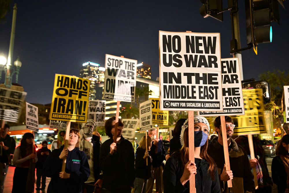 Demonstrators hold placards as they rally during a protest against military action in Iran outside of City Hall in Los Angeles, California, on March 2, 2026. (AFP)